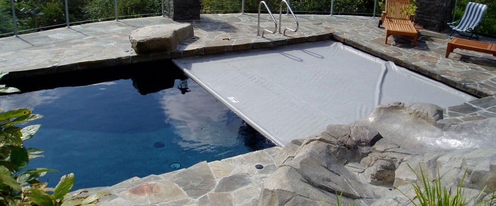 An automatic Coverstar inground pool cover is partially extended across an inground pool.