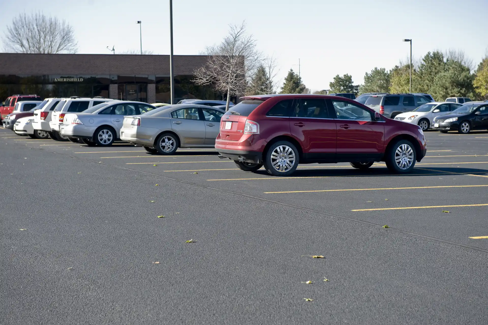 A parking lot newly paved with asphalt outside an Iowa business with several cars parked in it.