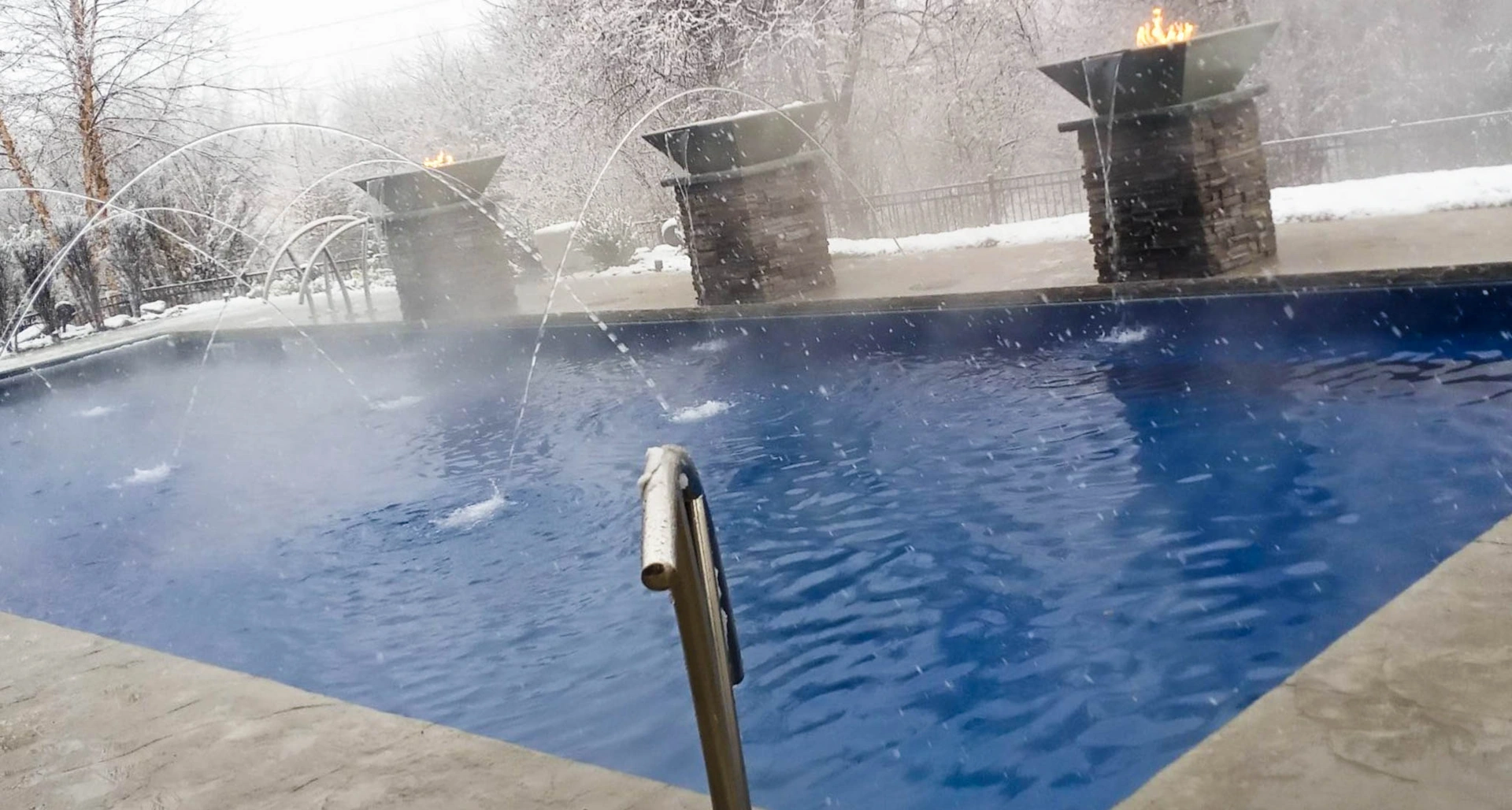 A rectangular inground pool with blue liner and deck jets sits in snowy Iowa outdoors. Conditions like these spark the question "Is a pool heater worth the investment?"