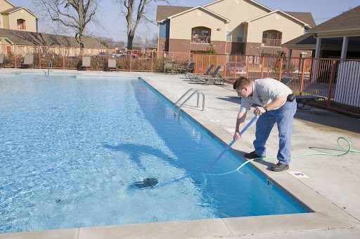 A professional technician from a pool route service vacuums out an inground pool