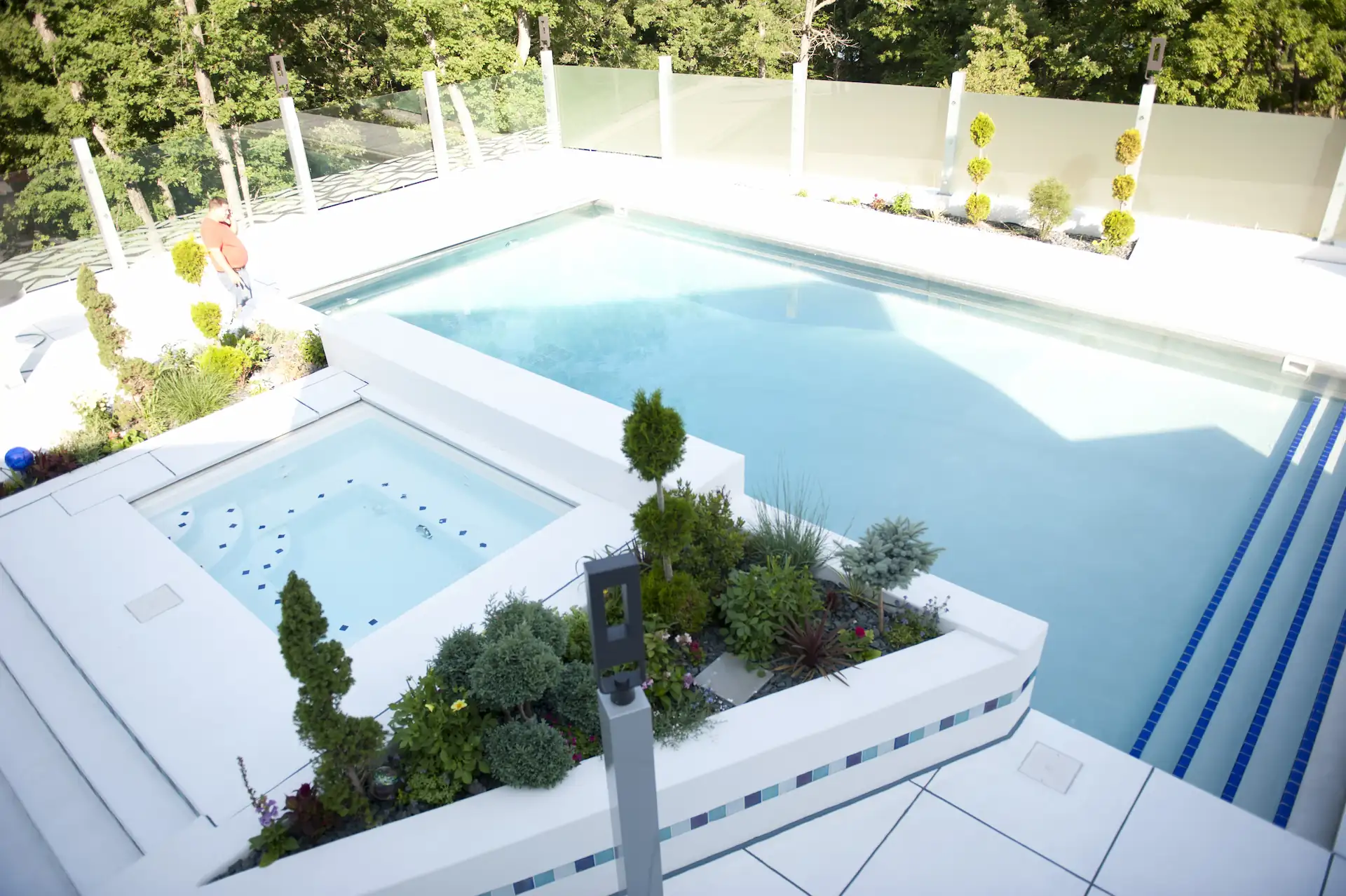 A concrete pool deck stamped with a crisp, white tile pattern surrounds a rectangular inground pool and spa.