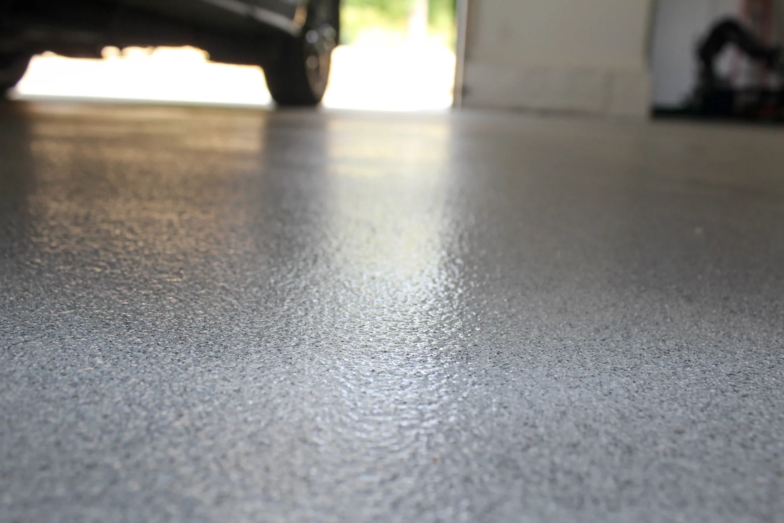 Close up on a garage floor coated with epoxy concrete. Garage floors are just one of the epoxy flooring applications for homes.