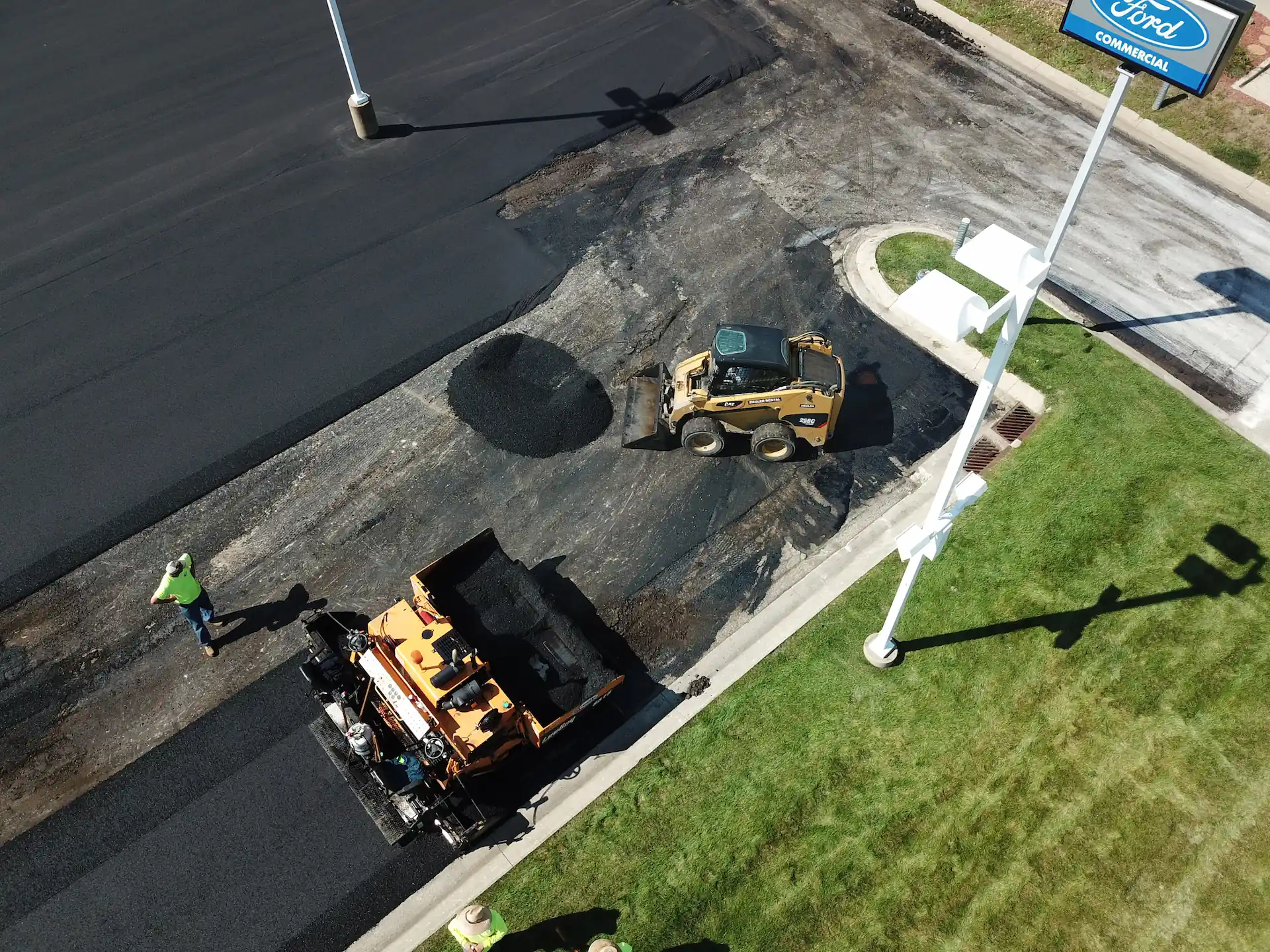 Aerial shot of a work crew from Speck USA paving an asphalt parking lot. Parking lot pavement is one of the critical elements that enhance your business's curb appeal.