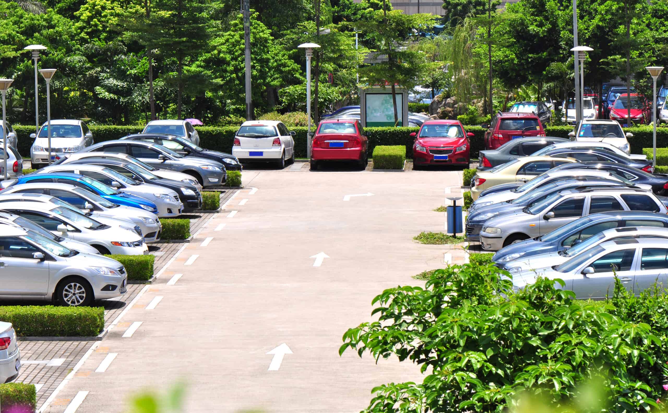 A pristine parking lot filled with cars and lovely landscaping shows why your parking lot should be a high priority for you business.